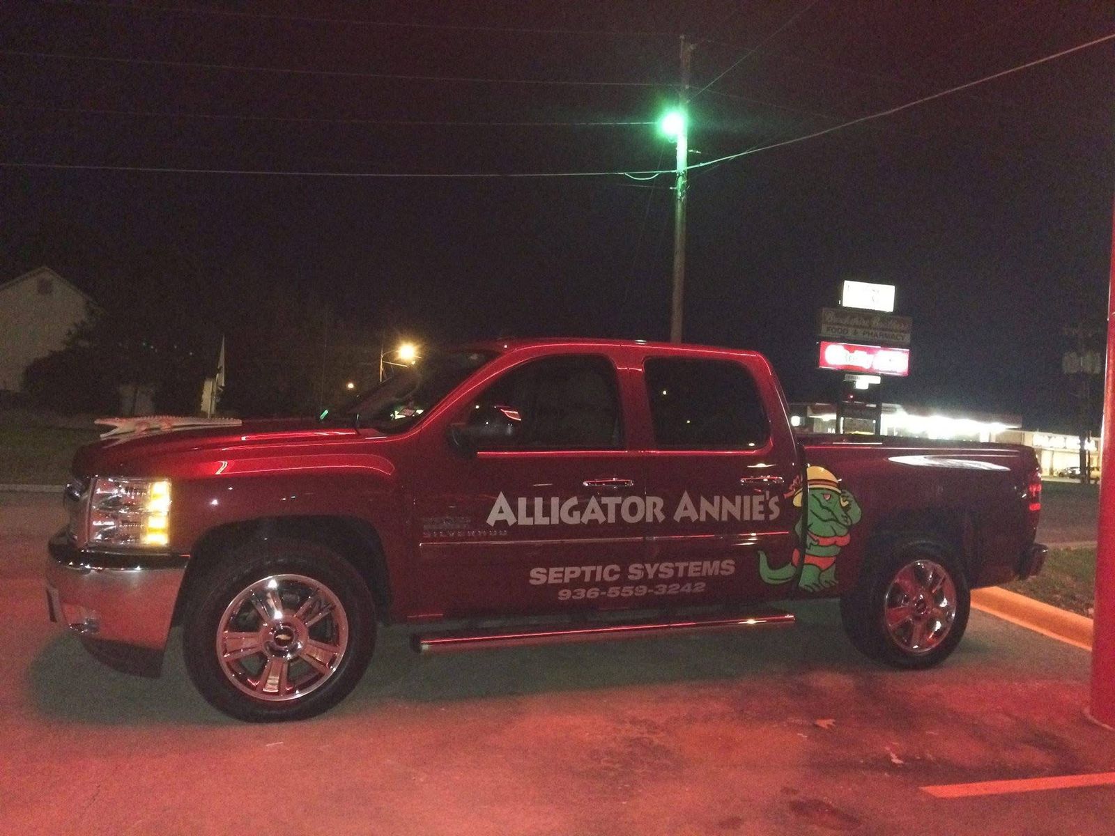 Maroon Chevrolet Silverado with an Alligator Annie&rsquo;s Septic Systems decal, parked at night